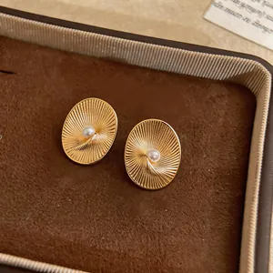 Detailed view of vintage oval textured gold stud earrings with a central pearl