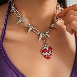 Dettaglio ravvicinato collana punk argento con borchie e ciondolo a cuore rosso