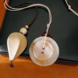 Gros plan détaillé de pendentifs en acrylique de style ethnique avec cordons sur du cuir.