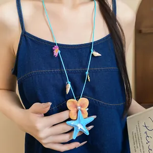 Detail of sunset bay starfish and shell flower necklace worn on a blue denim dress