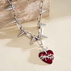 Primo piano di una collana a catena argentata con un cuore rosso avvolto da spine