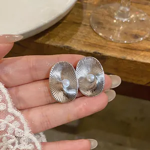 Detailed close-up of vintage oval textured earrings featuring elegant central pearl inlay