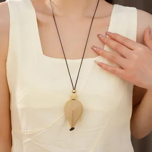 Gros plan d'un pendentif ethnique en forme de larme sur un long collier porté par un mannequin