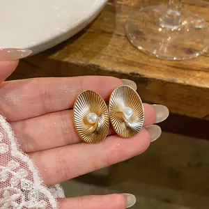 Macro view of elegant vintage gold ribbed oval stud earrings with a central pearl detail