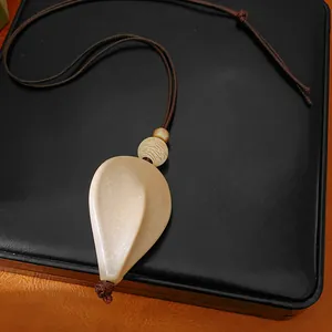 Gros plan d'un pendentif en acrylique crème de style ethnique sur cordon cuir.