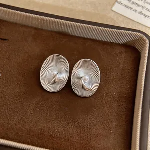 Close-up macro view of vintage style oval textured stud earrings with a central white pearl