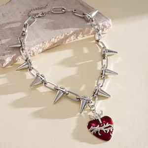 Primo piano di una collana gothic con borchie e ciondolo a cuore rosso con dettagli di spine.
