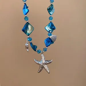 Nahaufnahme einer Strand-Perlenkette mit blauen Muscheln und silbernem Seestern-Anhänger