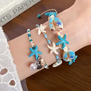 Elegant beach vacation style shell and starfish beaded bracelet set shown on a model wrist