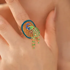Primo piano di un anello a pavone placcato oro 18K con smalto blu e verde vivace
