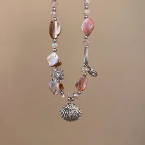Detailansicht einer Halskette im Strandstil mit rosa Muscheln und silbernem Anhänger.