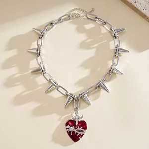 Dettaglio collana a catena con punte argento e ciondolo a cuore di spine rosso punk