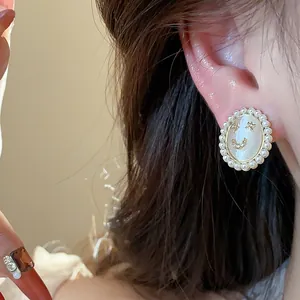 Close-up of elegant 14k gold plated smiley face earring with pearls and cat eye stone