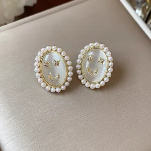 Detailed view of 14k gold plated smiley face earrings with pearls and cat eye stone