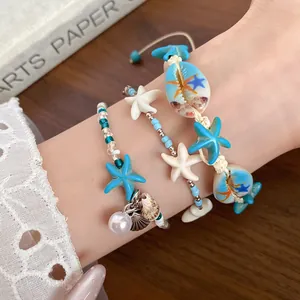 Macro detail of beach style bracelets featuring blue starfish charms and natural sea shells