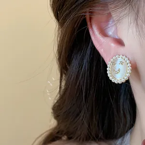 Close-up of elegant 14k gold plated smiley face stud earring with pearls and cat eye stone