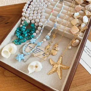 Detailed view of seaside style necklaces with shells, starfish and pearls in a tray