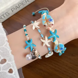Close-up view of beach style bracelets featuring blue starfish and white shells on wrist
