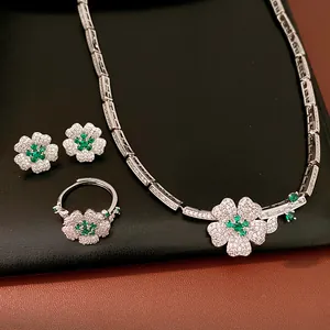 Detail view of a luxury jewelry set with green zircon floral necklace, ring, and earrings