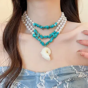 Detailed view of resort style necklace with turquoise chips, pearls, and shell pendant