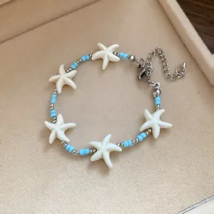 Detailed view of beach style bracelet featuring white starfish and light blue beads
