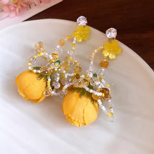 Élégantes boucles d'oreilles fleurs jaunes en tissu avec perles colorées et zircons