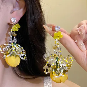 Gros plan détaillé des boucles d'oreilles fleur en tissu jaune avec perles et zircon