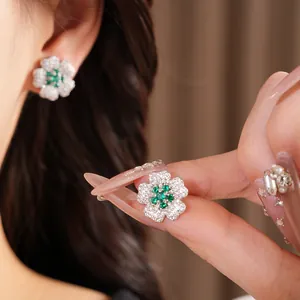 Detailed shot of a floral earring with green zircon center and clear pavé petals.