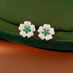 Exquisite close-up detail of emerald green and white zircon floral stud earrings on velvet