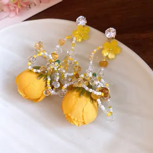 Vue détaillée de boucles d'oreilles rose en tissu jaune avec perlage fin et cristaux scintillants