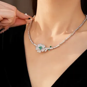 Close-up of elegant flower necklace with green and white zircons worn by a model