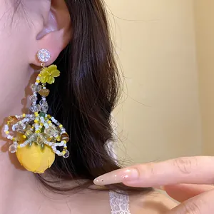 Gros plan boucle d'oreille fleur en tissu jaune avec clou en zircon étincelant