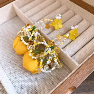 Gros plan détaillé de boucles d'oreilles fleurs en tissu jaune avec perles et zircon