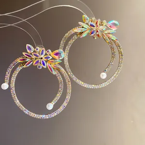 Close-up detail of silver needle earrings featuring iridescent rhinestones and elegant white pearls