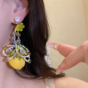 Gros plan de boucles d'oreilles fleur en tissu jaune avec clous en zircon et perles