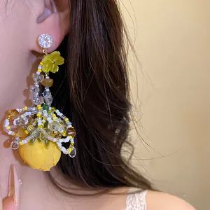 Vue détaillée des boucles d'oreilles fleur en tissu style vacances avec zircon et perles.