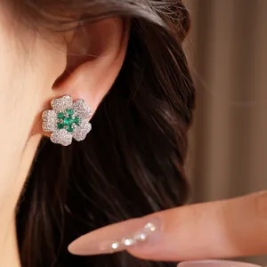 Close-up detail of luxury emerald green and white zircon flower stud earring worn on ear