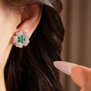 Detailed close-up view of elegant green zircon flower stud earrings worn on a model's ear