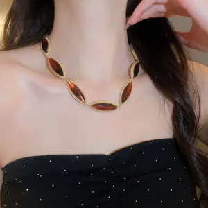 Detailed view of an elegant marquise-cut amber stone necklace on a female model's neck