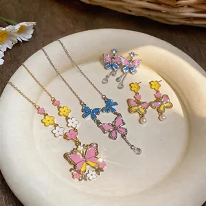 Vibrant enamel butterfly and flower necklace and earrings set on a decorative plate