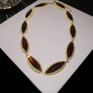 Elegant gold-tone necklace with marquise-cut dark red gemstones and beaded trim