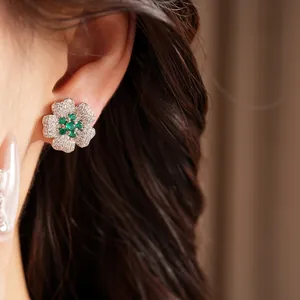 Detailed view of luxury flower stud earring with green and white zircons on ear