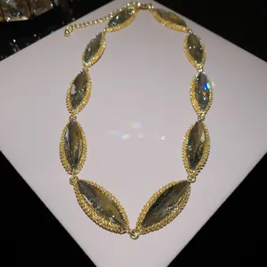 Detailed close-up of a marquise-cut grey crystal necklace with gold textured setting.
