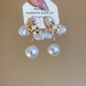 Close-up of elegant 18k gold plated floral earrings with lustrous white pearl drops