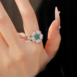 Macro view of a luxury silver flower ring featuring emerald green and clear zircons.