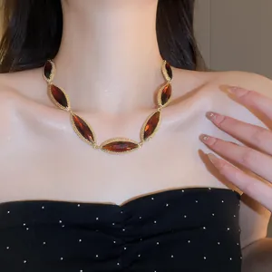 Close-up of high-end oval amber crystal necklace with gold metal trim on a female neck