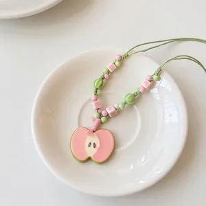 Handmade pink ceramic apple pendant necklace with green beaded cord and woven rope