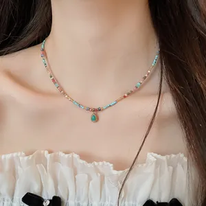 Nahaufnahme einer farbenfrohen Boho-Perlenkette mit Tropfenanhänger am Hals des Modells.