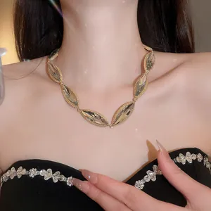 Macro view of a gold necklace with large elliptical faceted crystals on a model