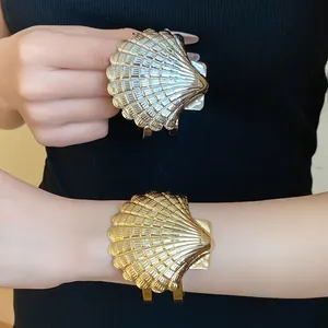 Primer plano de brazaletes de metal dorados y plateados con forma de caracola